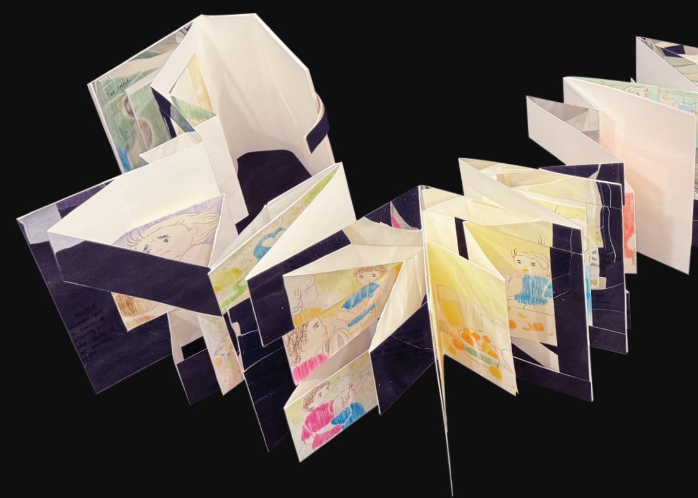 Handmade concertina book standing open on black, its folded panels holding coloured pencil drawings