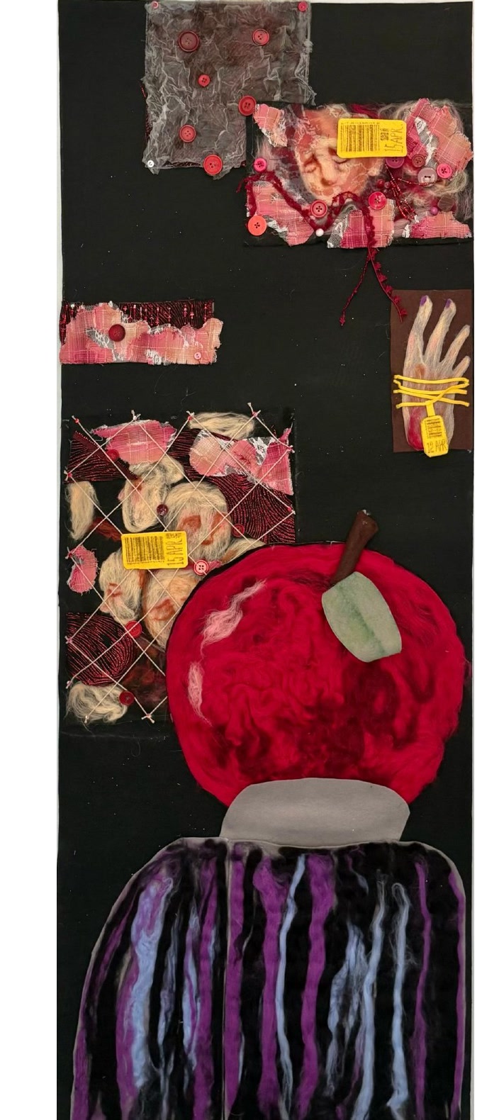 Tall black wool-felt hanging piece with stitched body fragments, labels, and a large red apple form